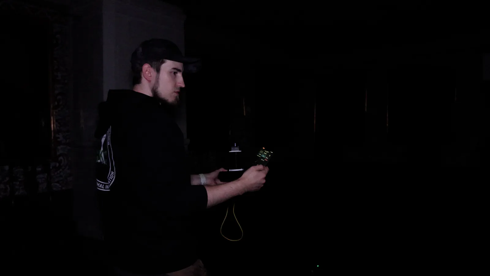 Joen holding a small home-built electronic device in a dark room