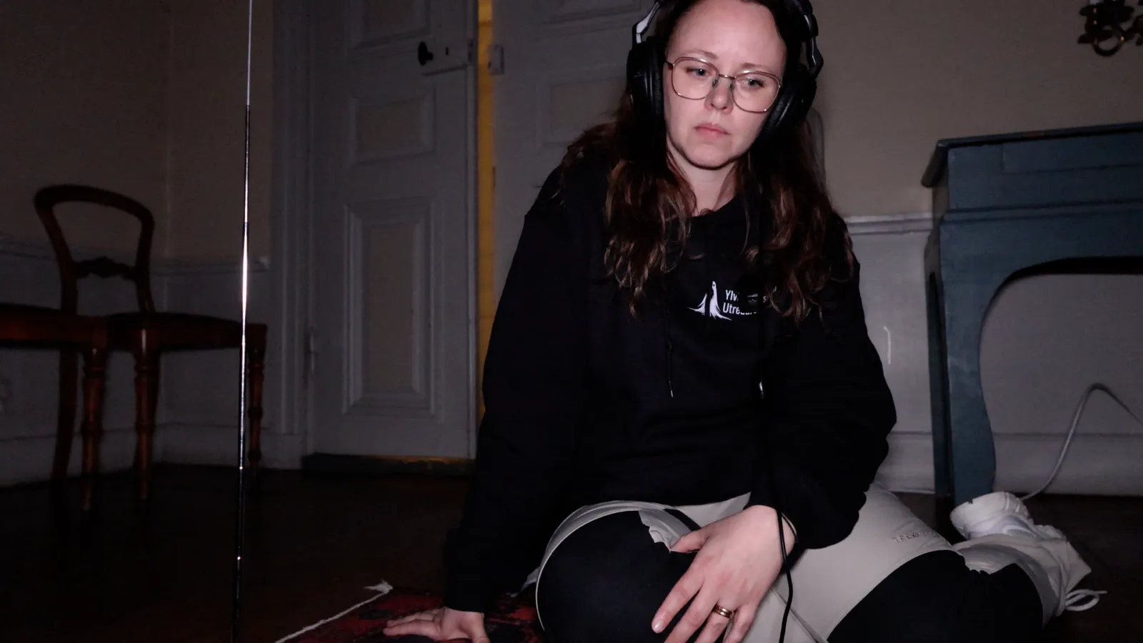 Ylva sitting on the floor with headphones, listening back to a recording during an investigation