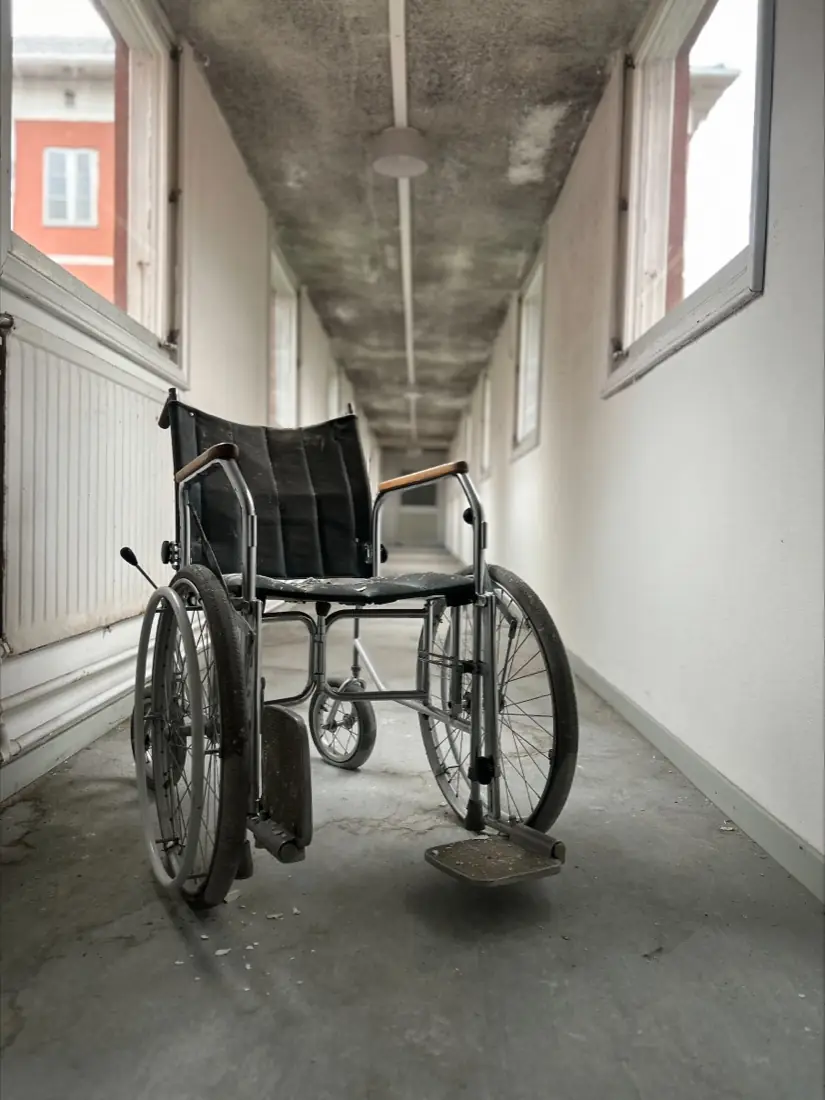 A wheelchair left standing in a bright corridor at Sandträsk sanatorium